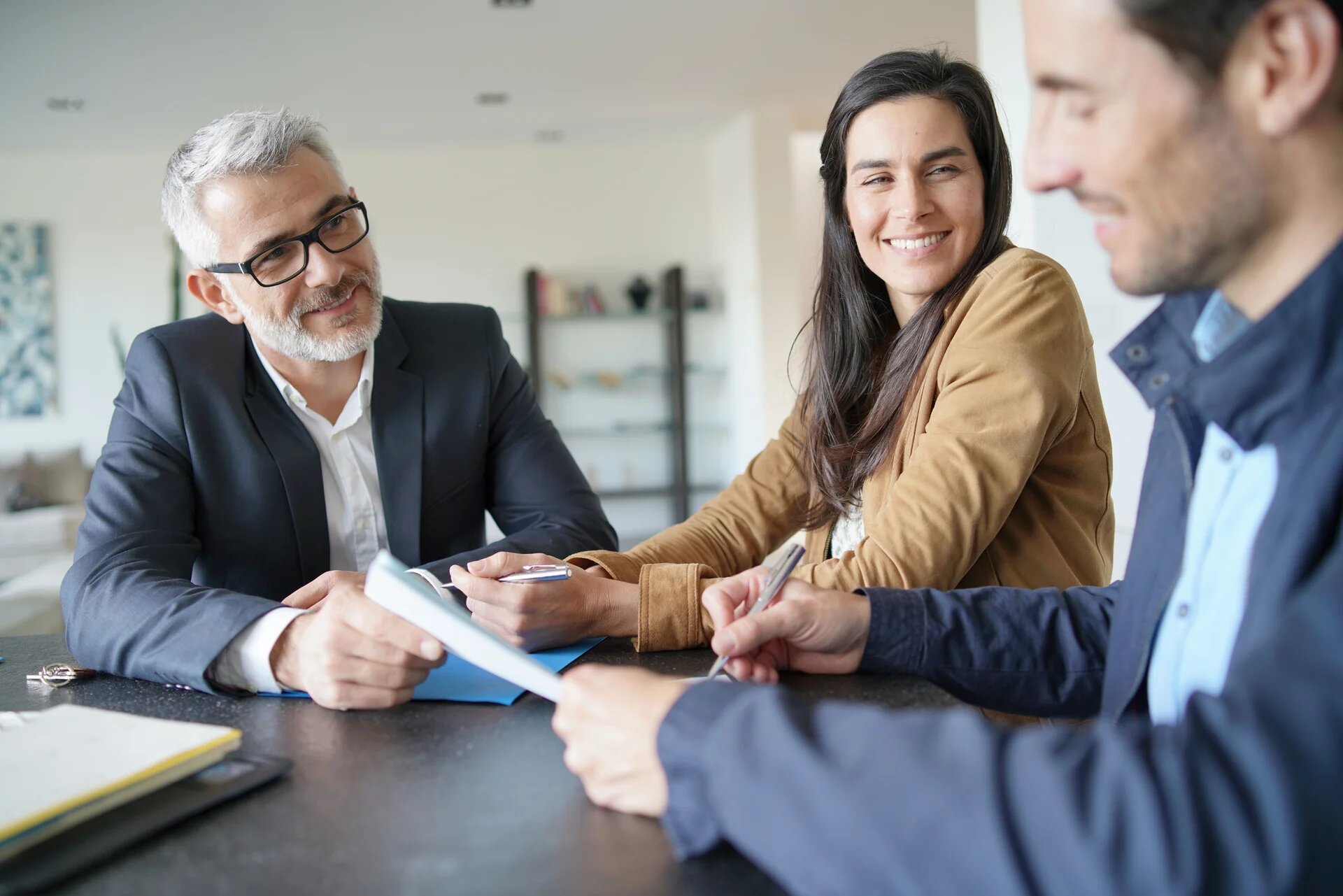 3 personnes autour d'un bureau. L'un des 3 signe un document